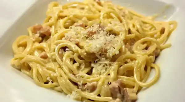 Pyszne spaghetti carbonara z kawałkami boczku i parmezanem. Idealna odpowiedź na pytanie: jaka śmietana do carbonary?