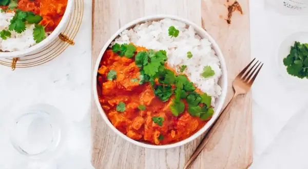 Pyszny kurczak w sosie curry z ryżem, udekorowany świeżą kolendrą. Prosty przepis na szybki obiad.