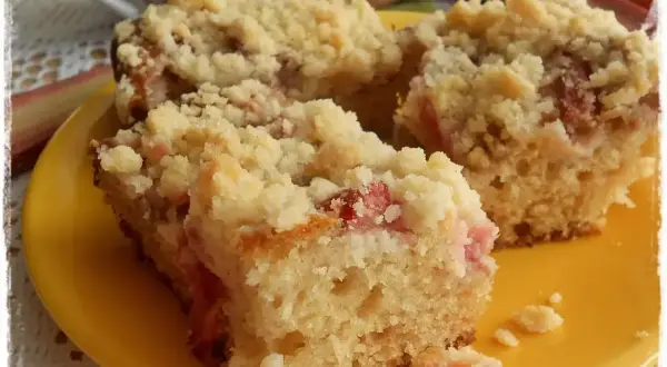 Szybkie ciasto jogurtowe z rabarbarem i kruszonką, podane na żółtym talerzyku. Idealne na letnie popołudnie.