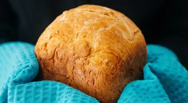 Złocisty chleb z airfryer, pachnący świeżością, otulony turkusowym ręcznikiem. Idealny na śniadanie.