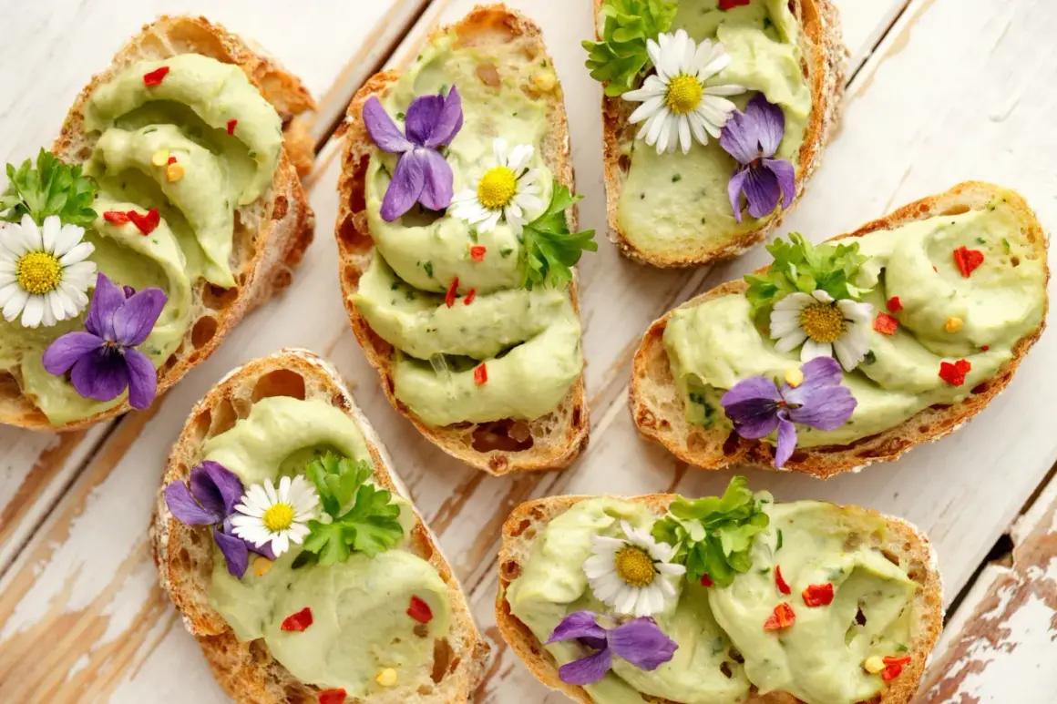 Pyszne **finger food**: grzanki z awokado, ozdobione kwiatami i ziołami. Idealne na wiosenne przyjęcie.