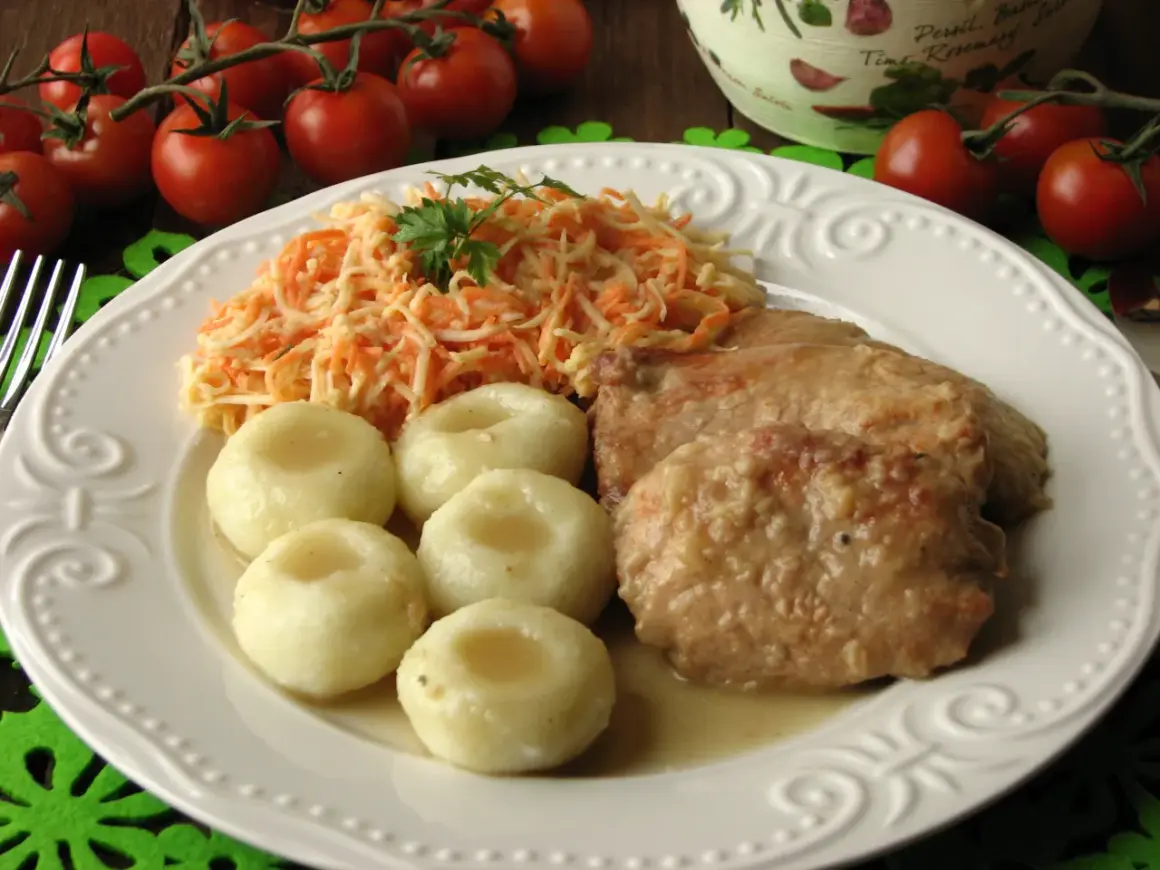 Bitki wieprzowe w sosie własnym z cebulką, podane z kluskami śląskimi i surówką z marchewki. Pyszny, domowy obiad.
