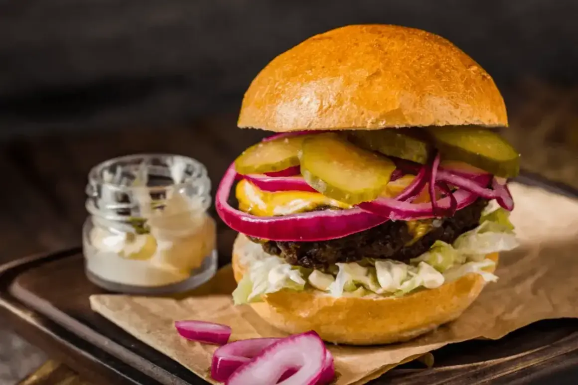 Pyszny hamburger z soczystą wołowiną, chrupiącą sałatą, piklami, czerwoną cebulą i majonezem. Idealny przepis na to, jak zrobić hamburgera.