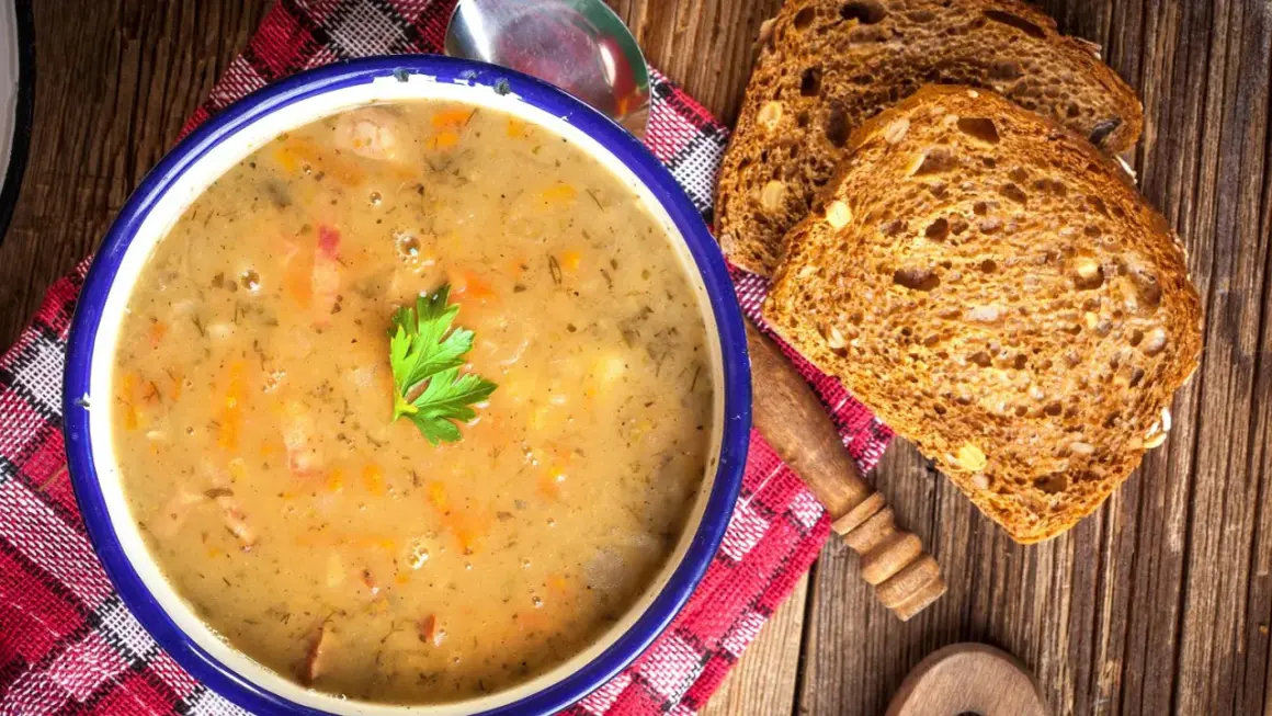 Aksamitna zupa grochowa, przepis babci, z kawałkami wędzonki i natką pietruszki, podana z chlebem żytnim.