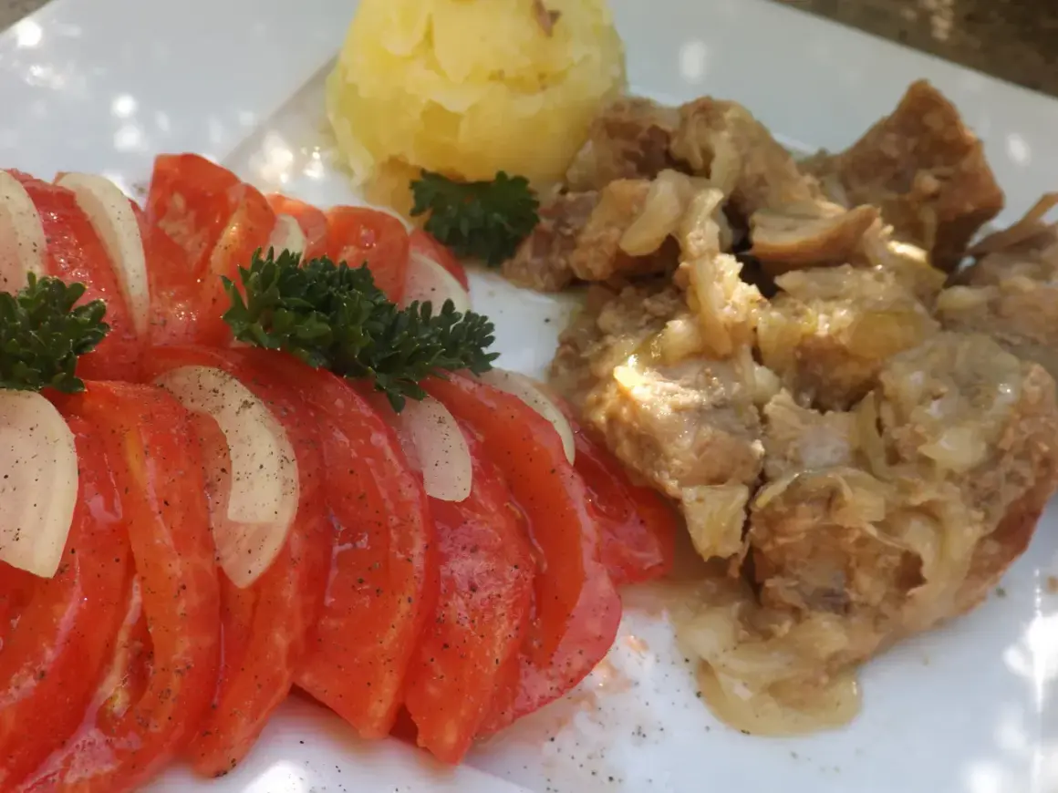 Świeżonka duszona z cebulką, podana z ziemniakami i sałatką z pomidorów i cebuli.