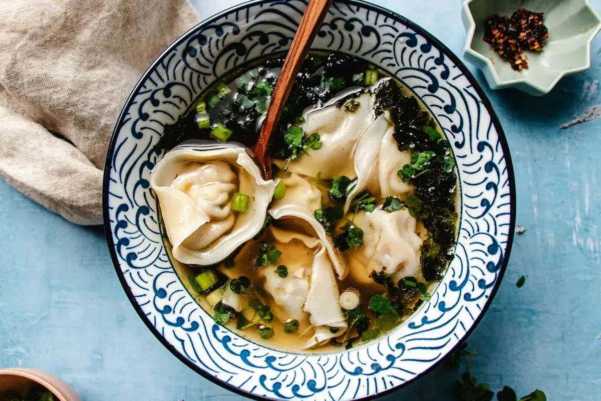 Aksamitna zupa won ton z delikatnymi pierożkami, zieloną cebulką i wodorostami. Idealna na chłodne dni.
