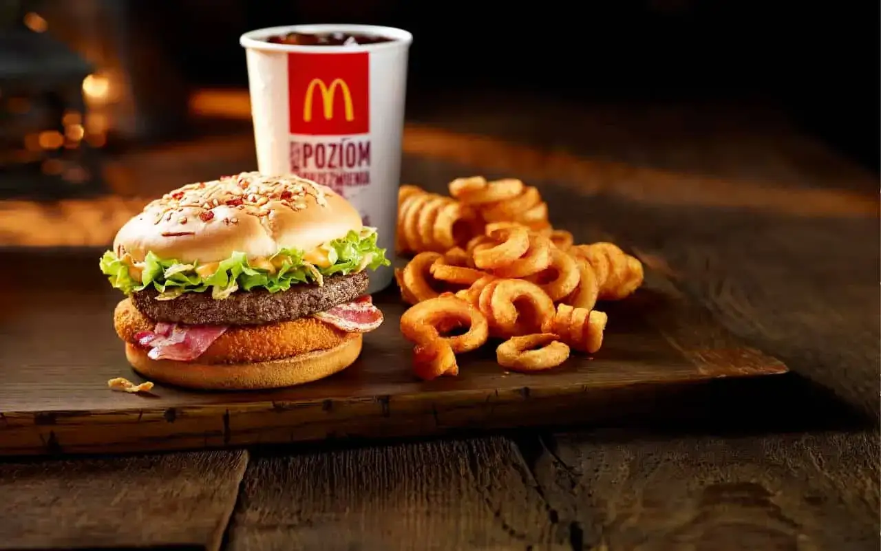 Burger drwala z chrupiącym kurczakiem, bekonem i wołowiną, podany z kręconymi frytkami i napojem.