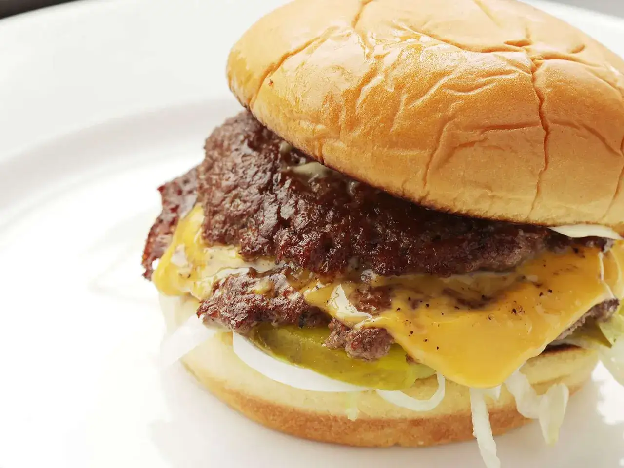 Pyszny smash burger co to? Podwójna, rozgnieciona wołowina, topiony ser cheddar, pikle i cebula w miękkiej bułce.