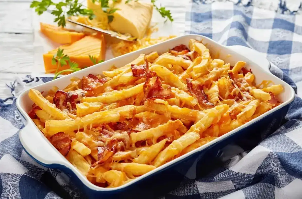 Chrupiące frytki z serem i bekonem w naczyniu żaroodpornym, gotowe do podania.