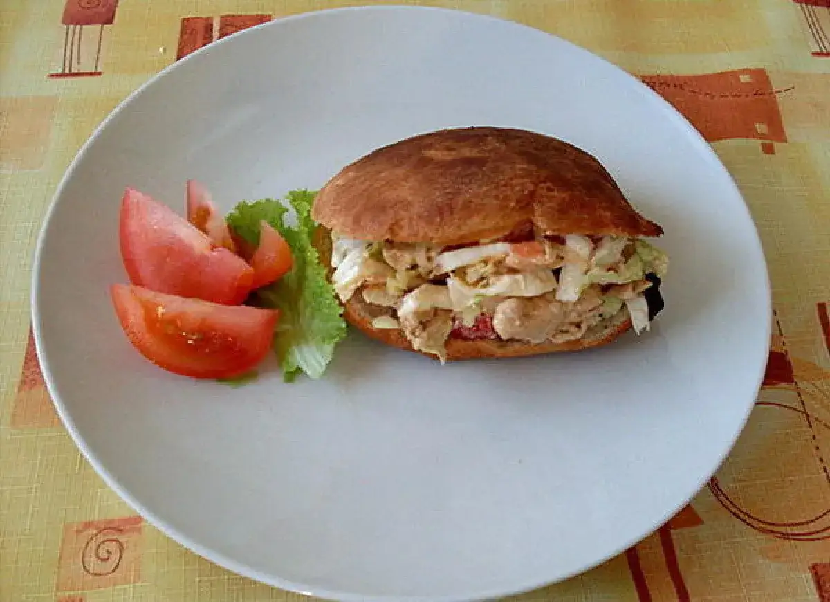 Pyszny kebab w picie z soczystym mięsem, chrupiącą sałatką i świeżymi pomidorami na białym talerzu.
