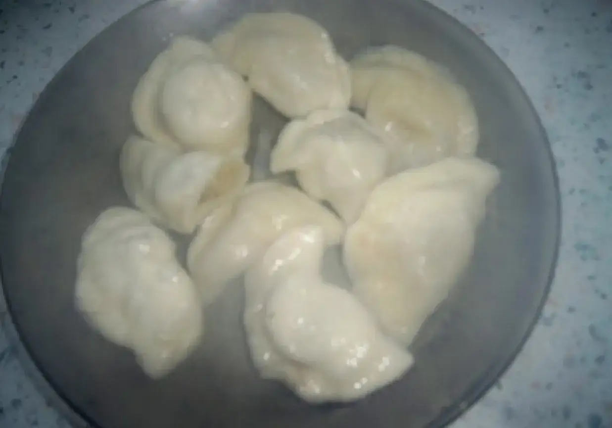 Parujące pierogi z ciasta bez jajka, ułożone na talerzu.