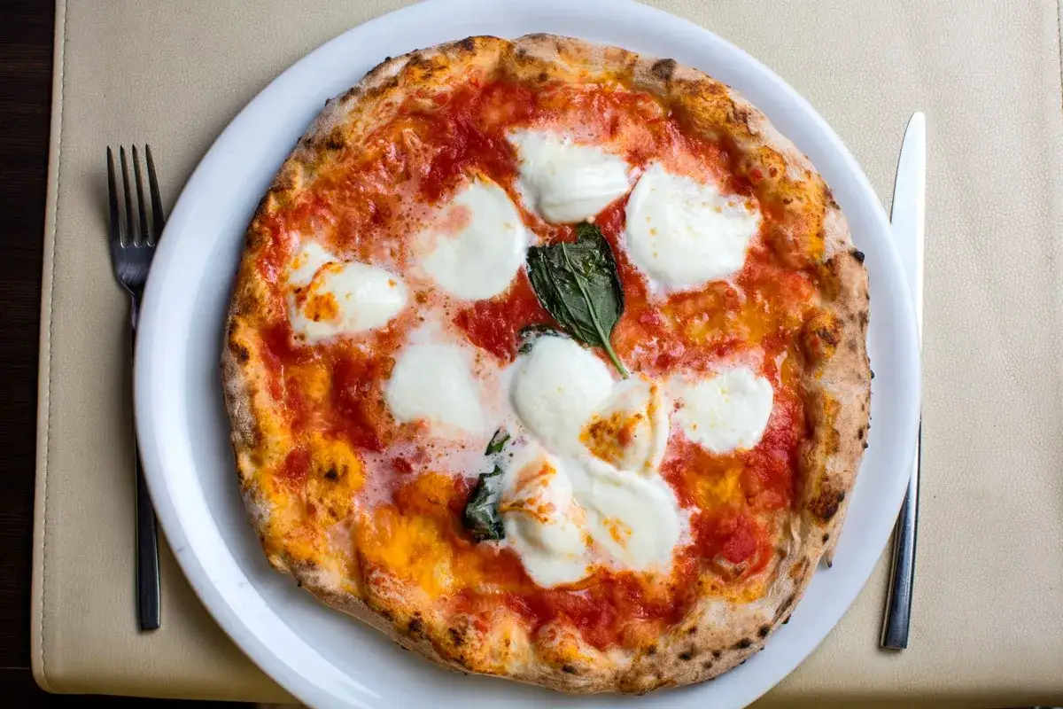 Pyszna pizza Margherita, klasyczny włoski przepis. Sos pomidorowy, mozzarella i bazylia na chrupiącym cieście.