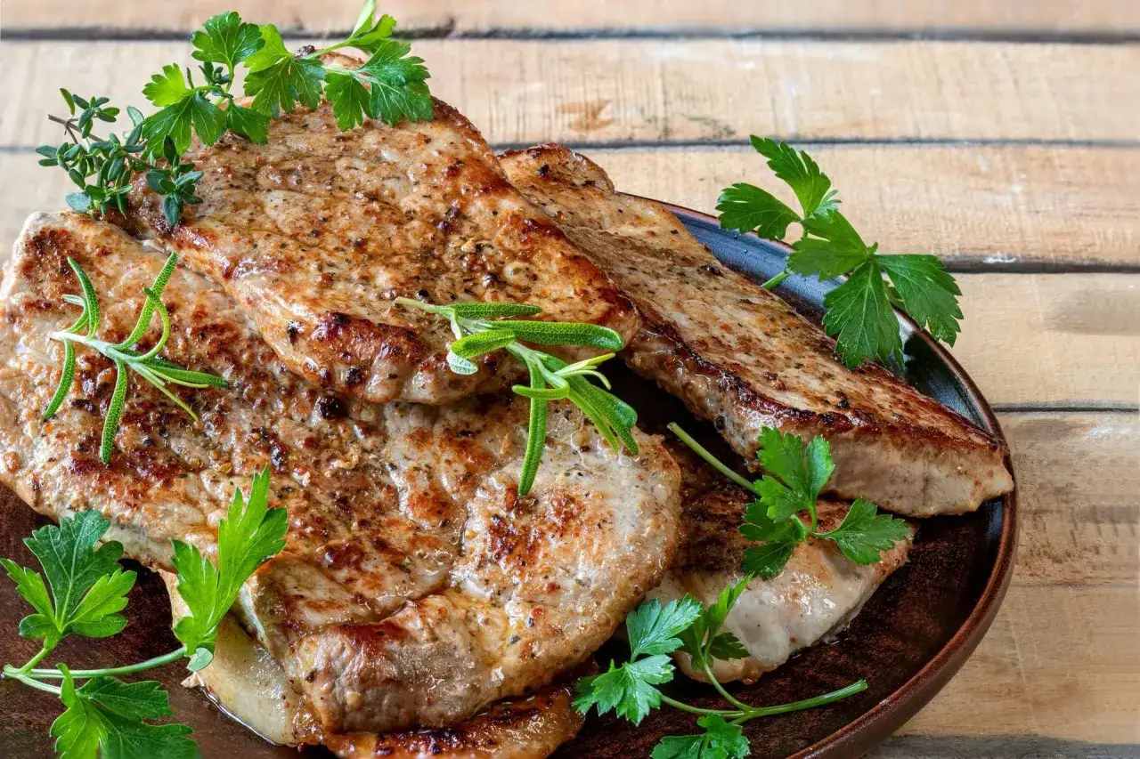 Soczysty schab w airfryer, idealnie przypieczony, z gałązkami rozmarynu i natki pietruszki. Pyszny obiad gotowy w mgnieniu oka!