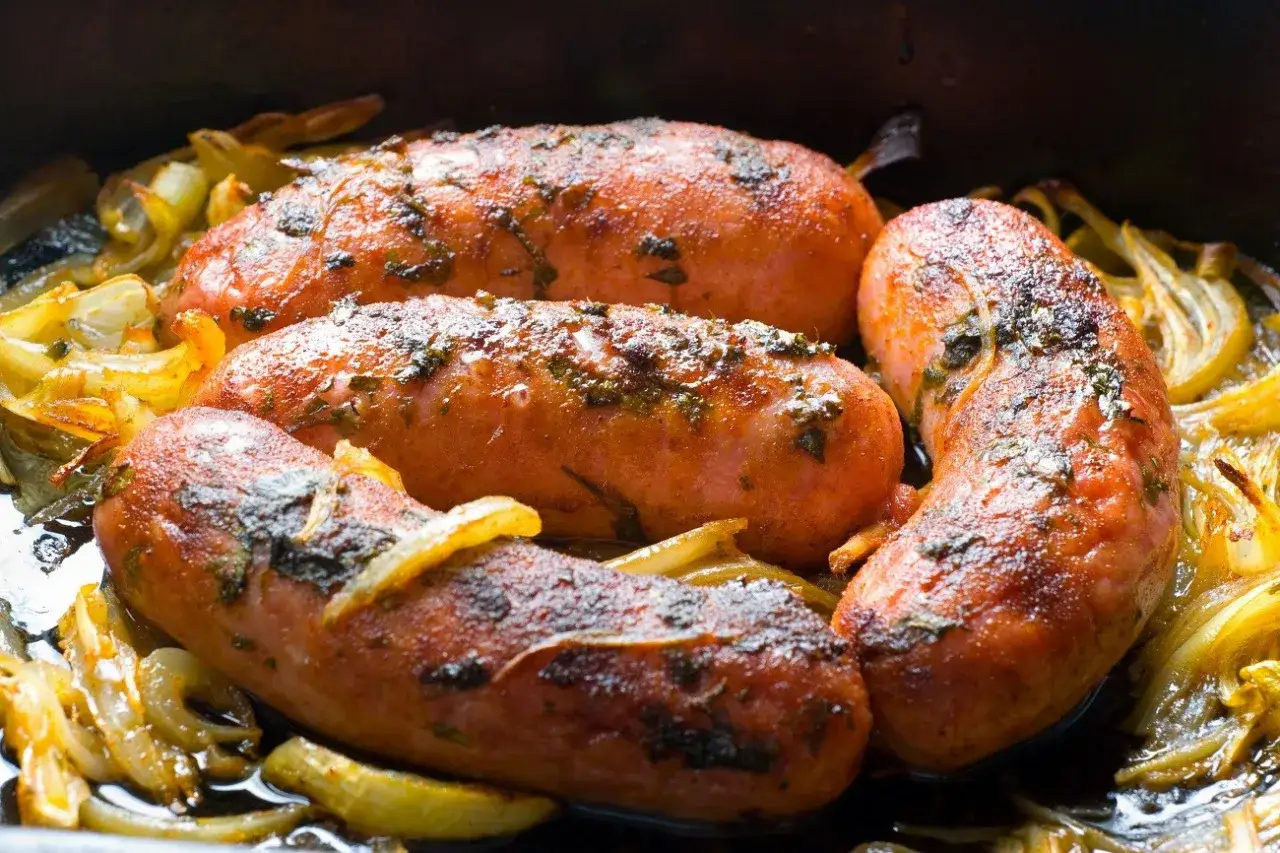 Soczysta kiełbasa z piekarnika jak z grilla, pieczona z cebulką. Idealna na obiad.