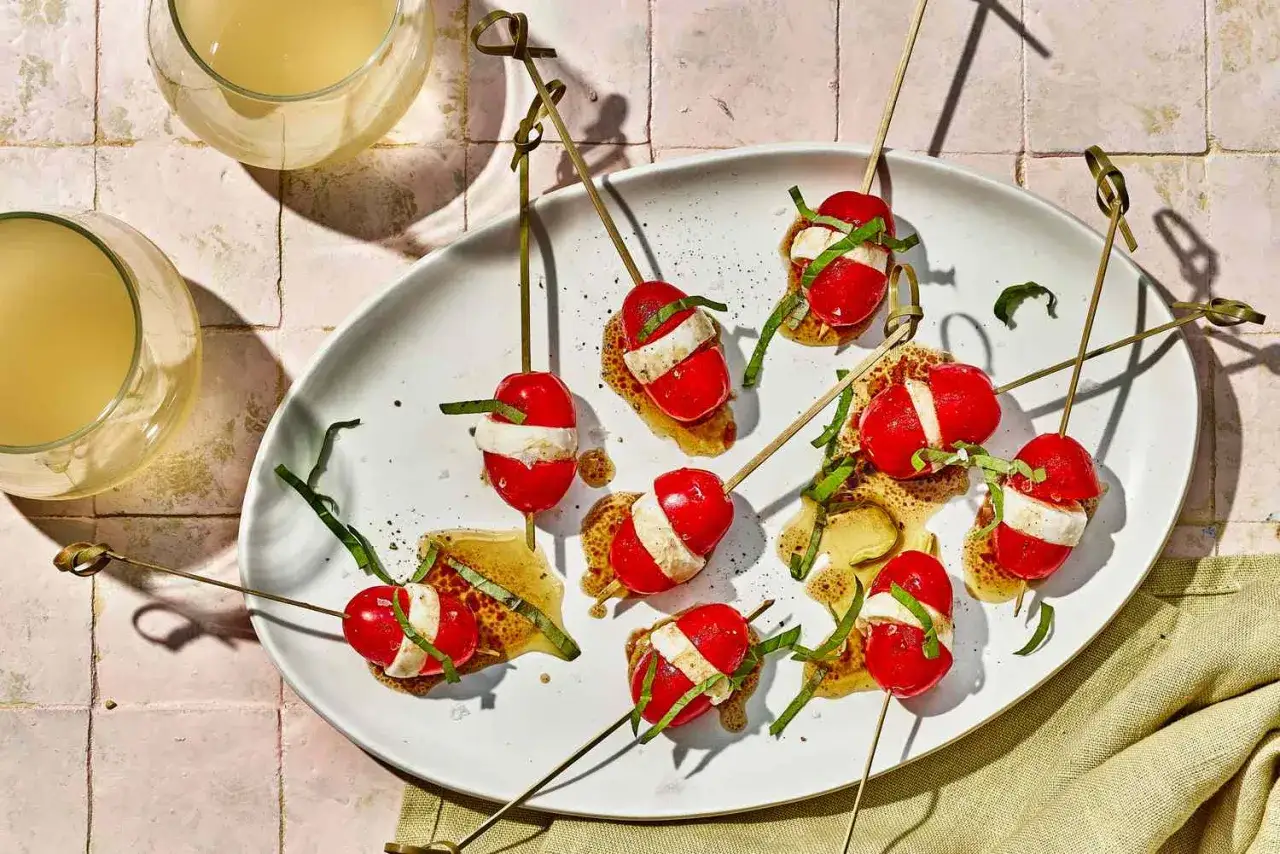 Pyszne finger food: pomidorki koktajlowe z mozzarellą i bazylią na patyczkach, polane sosem. Idealne na przyjęcie!
