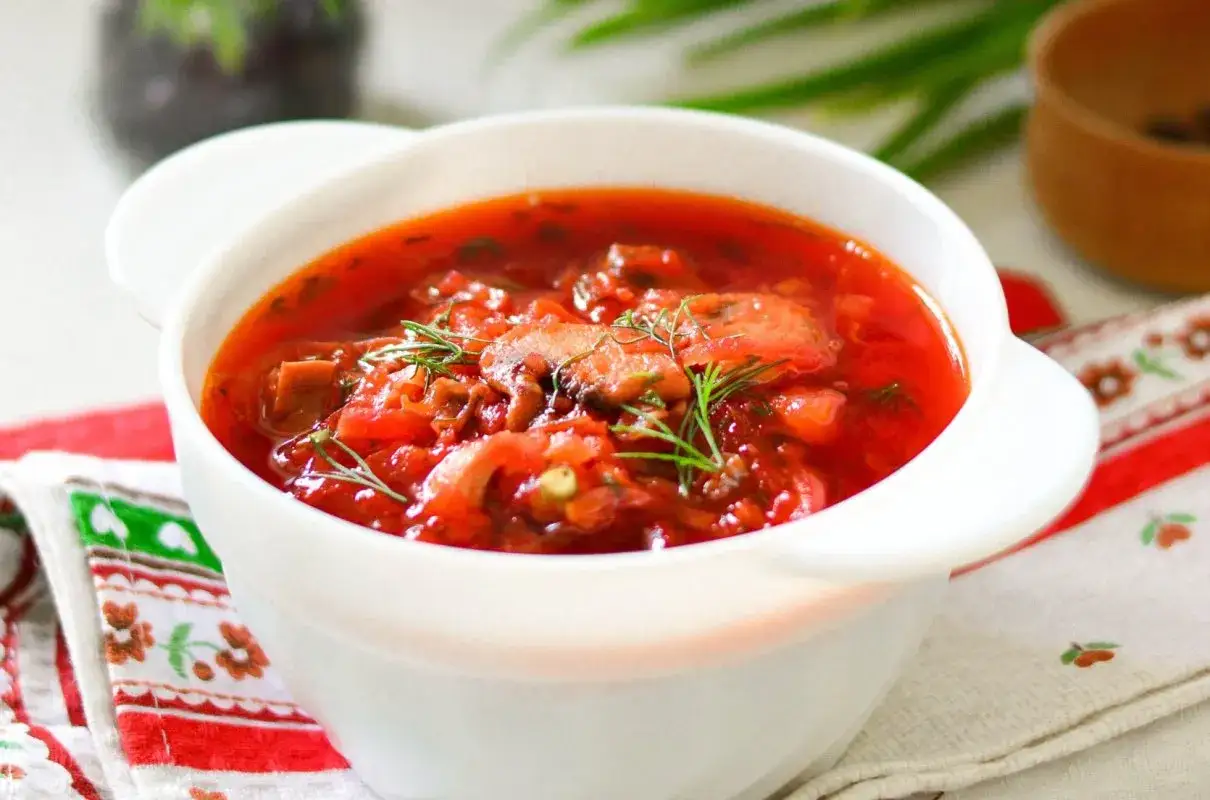 Aromaticzny barszcz ukraiński tradycyjny w białej miseczce, ozdobiony koperkiem. Idealny przepis na rozgrzewający posiłek.
