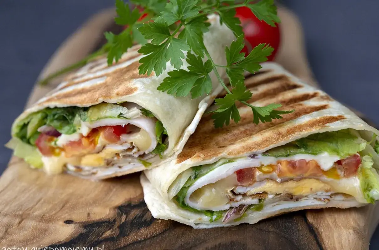 Szybka kolacja z niczego: pyszny wrap z kurczakiem, jajkiem, serem, pomidorem i sałatą, udekorowany natką pietruszki.