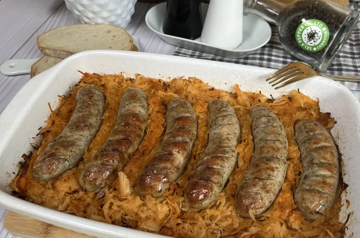 Pyszna biała kiełbasa z kapustą kiszoną zapieczona w naczyniu. Idealny obiad, który rozgrzewa i syci.