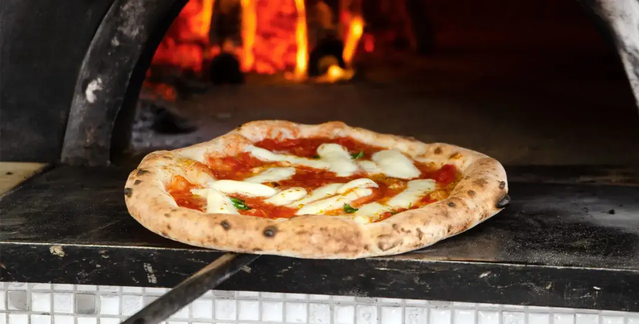 Pyszna pizza napoletana z roztopioną mozzarellą i sosem pomidorowym, pieczona w piecu opalanym drewnem.