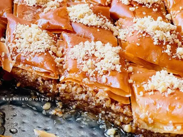 Słodka baklava, co to? Warstwy ciasta filo, orzechów i syropu miodowego, posypane kruszonymi orzechami. Pyszny deser!