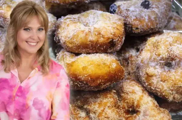 Uśmiechnięta Ewa Wachowicz prezentuje swoje pączki z ziemniakami, obficie posypane cukrem.
