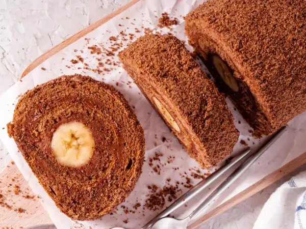 Czekoladowa, najprostsza rolada biszkoptowa z bananem w środku, posypana wiórkami. Idealna na deser.