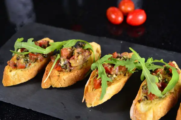 Cztery chrupiące bruschetty z pomidorami, ziołami i rukolą. Idealne tapas, co to jest? Pyszna przekąska!