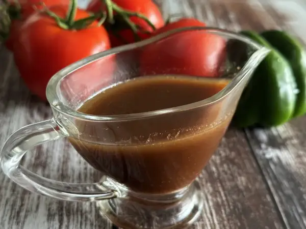 Sos balsamiczny w sosjerce, na tle pomidorów i zielonej papryki. Idealny do sałatek i mięs.