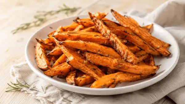 Chrupiące bataty z airfryer, przyprawione rozmarynem, wyglądają apetycznie na białym talerzu.