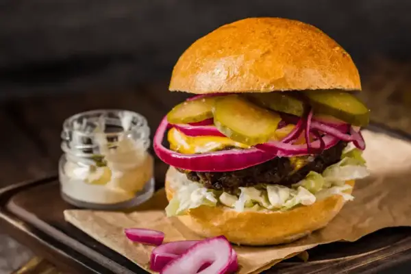Pyszny hamburger z soczystą wołowiną, chrupiącą sałatą, piklami, czerwoną cebulą i majonezem. Idealny przepis na to, jak zrobić hamburgera.