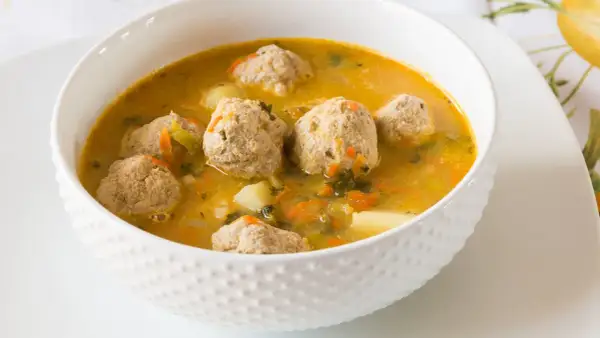 Zupa klopsowa babci: aromatyczny bulion z klopsikami, ziemniakami i warzywami. Smak dzieciństwa w miseczce.