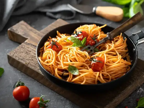 Pyszne spaghetti z pomidorkami i bazylią, idealne na smaczne obiady domowe przepisy. Widok z góry na talerz pełen makaronu.