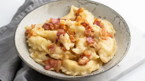 Pyszne pierogi ruskie z farszem Magdy Gessler, okraszone skwarkami i cebulką.