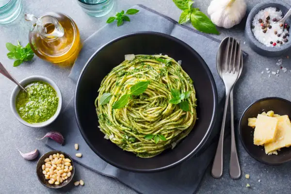 Pyszny obiad bez mięsa: spaghetti z pesto, świeżą bazylią, orzeszkami pinii i parmezanem.